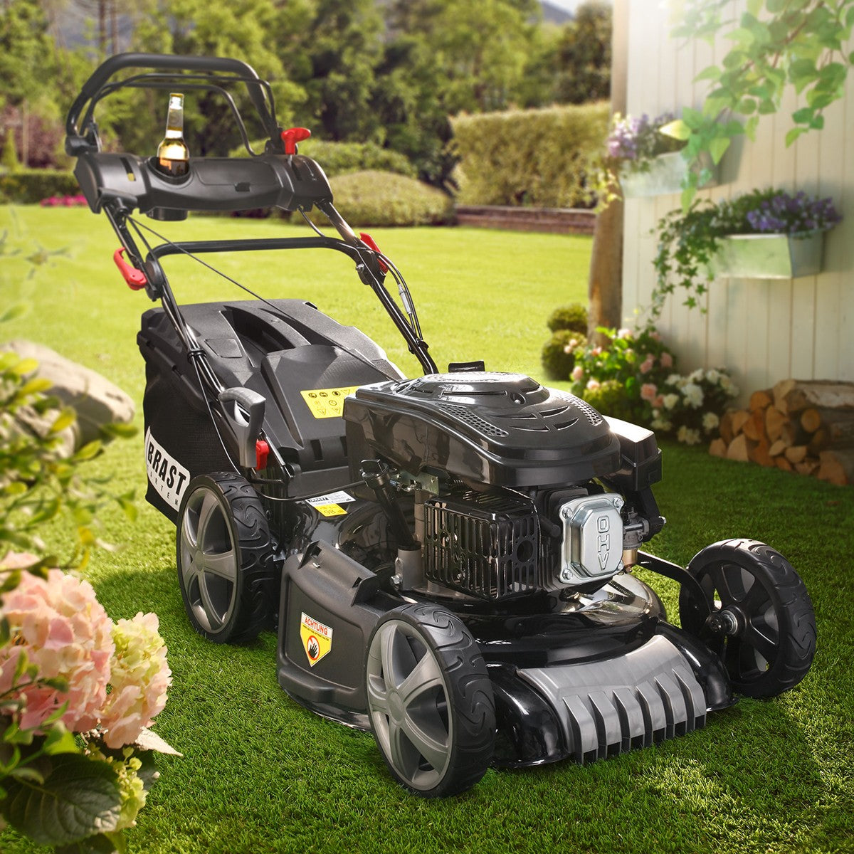 Schwarzer Benzin-Rasenmäher mit großem Grasfangkorb und robusten Hinterrädern auf grünem Rasen.