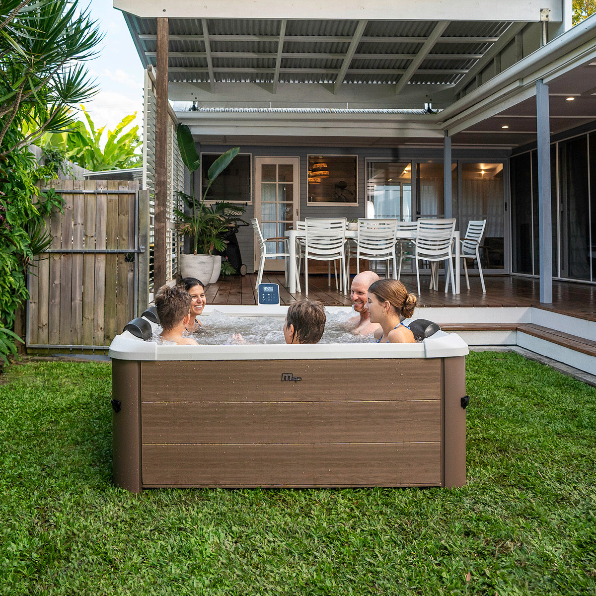 Brauner BRAST Mspa Oslo Amber Whirlpool Outdoor für 6 Personen mit fester Außenwand und LED im Garten.