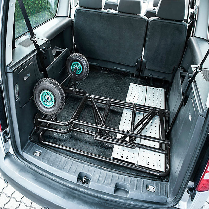 Kompaktes mobiles Arbeitsgerüst aus schwarzem Metall mit Rollen, zusammengeklappt im Kofferraum eines Autos.