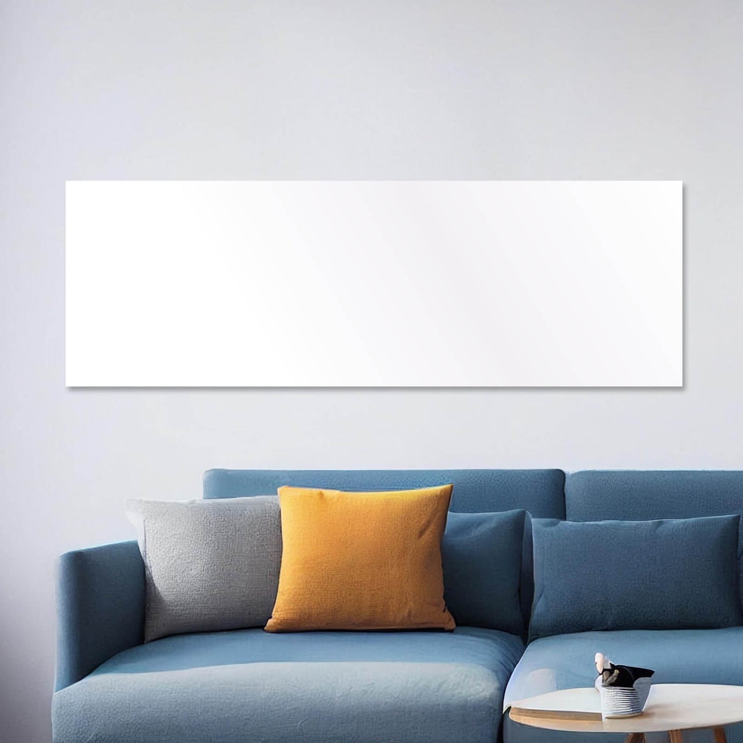 Weiße flache Hybrid Infrarotheizung ISP-HB 550 an heller Wand über blauem Sofa mit bunten Kissen.