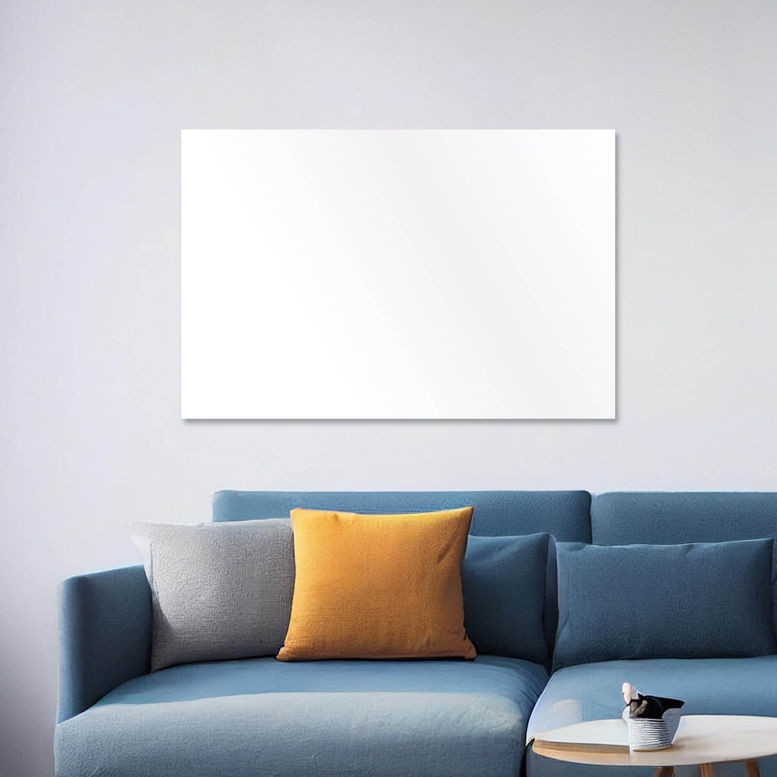 Weiße rechteckige Hybrid Infrarotheizung über blauem Sofa mit grauem und orangefarbenem Kissen.