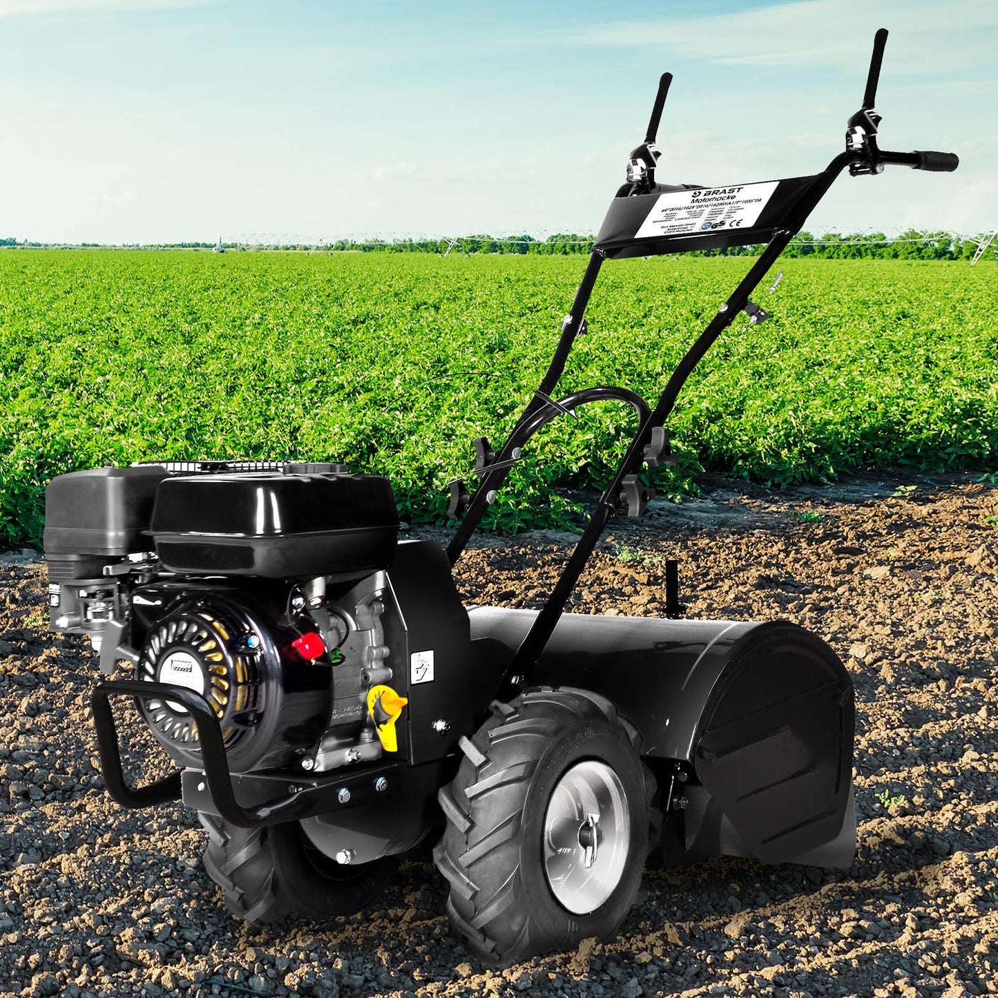 Schwarze Benzin Gartenfräse mit Motorhacke, großen Reifen und Bodenfräse Pflug vor grünem Feld.