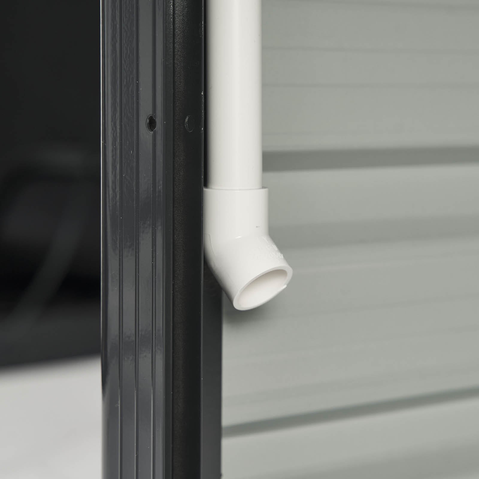 Detailansicht eines weißen PVC-Rohranschlusses am Aluminium Gewächshaus mit robustem Fundament.