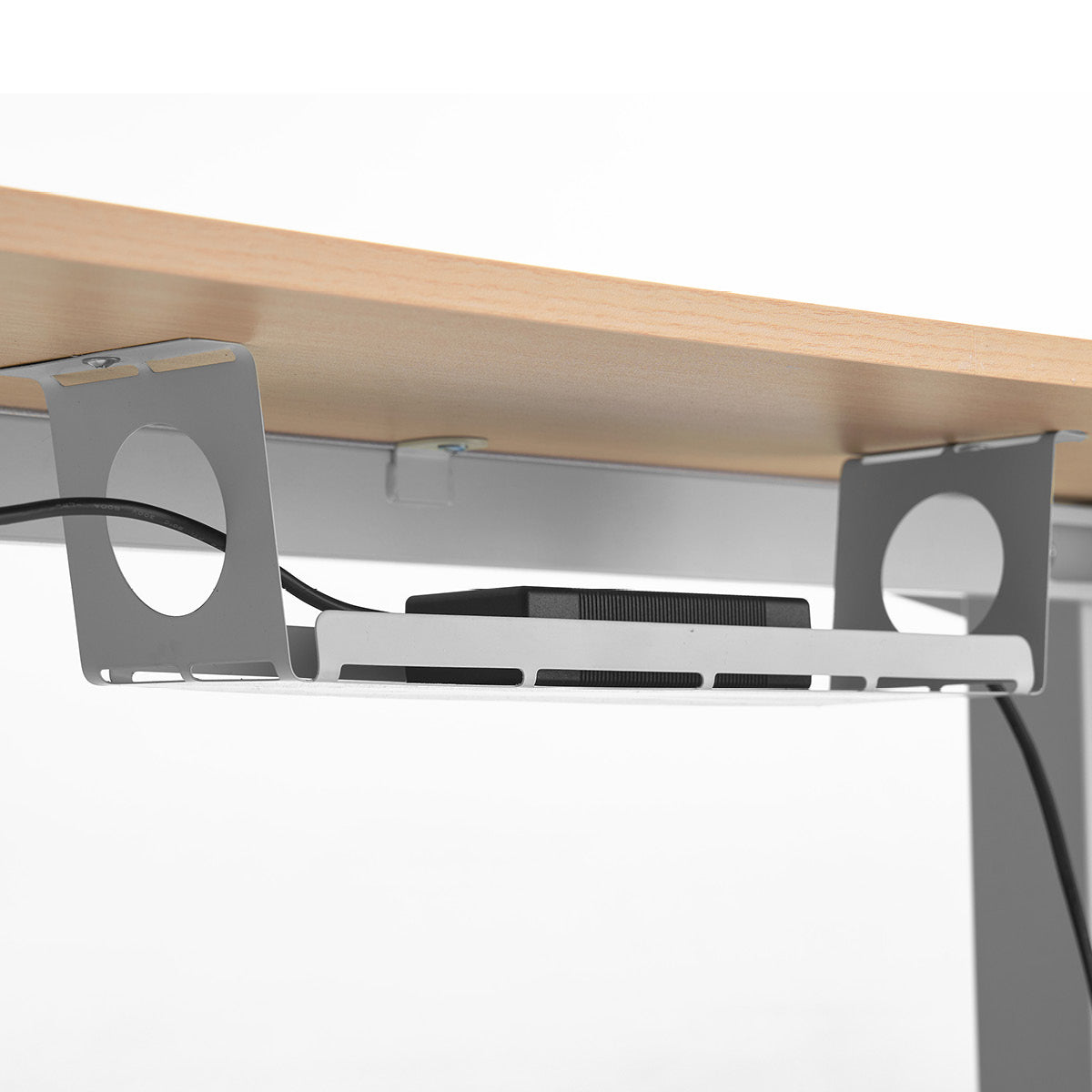 Höhenverstellbarer Schreibtisch mit heller Ahornplatte und darunter befestigtem grauem Laptophalter aus Metall.
