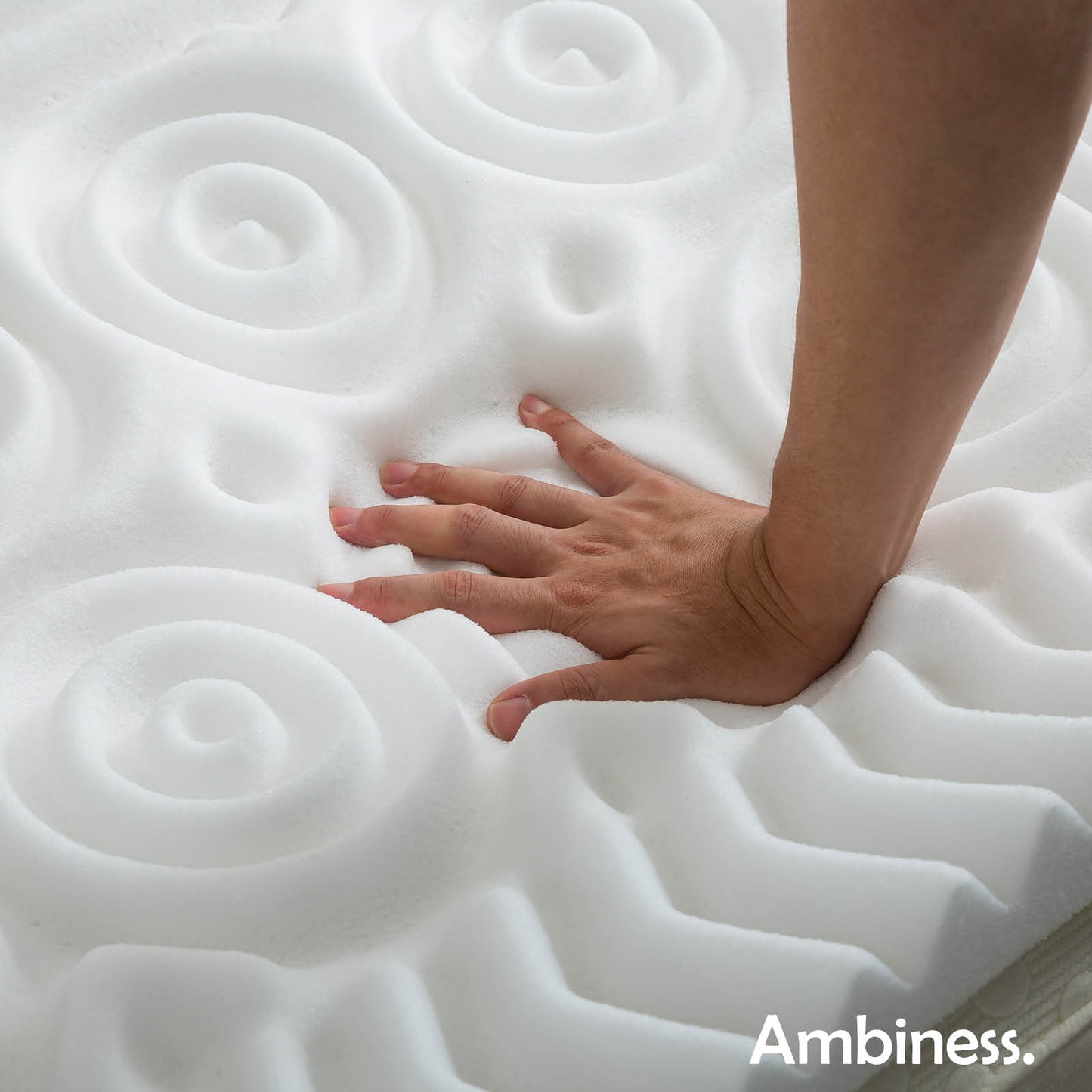 Weißer Matratzen Topper mit 13 Zonen und Memory-Schaum, Hand drückt die Oberfläche ein.