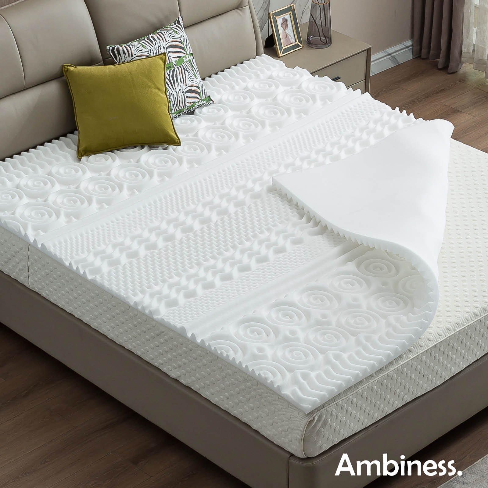 Weißer Matratzen Topper aus Memory Schaum mit 13 Zonen, auf grauem Bettgestell liegend.