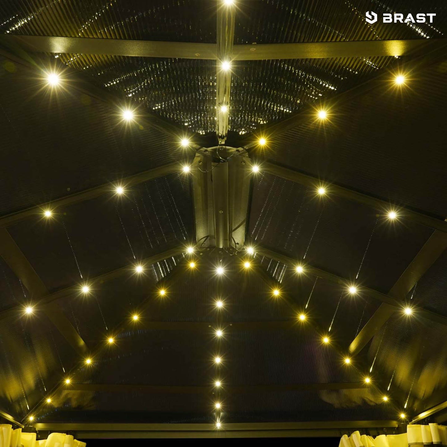 Großer grauer Aluminium-Pavillon mit LED-Beleuchtung und dunklem Dach, beleuchtet von warmen Lichtern.