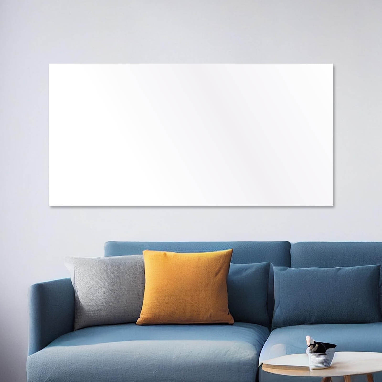 Weiße rechteckige Hybrid Infrarotheizung über blauem Sofa mit grauem und orangem Kissen.